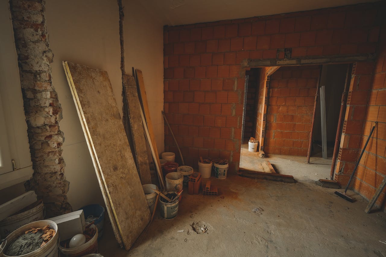 about-us-02 A red brick wall under construction with tools and materials scattered around in a renovation project.