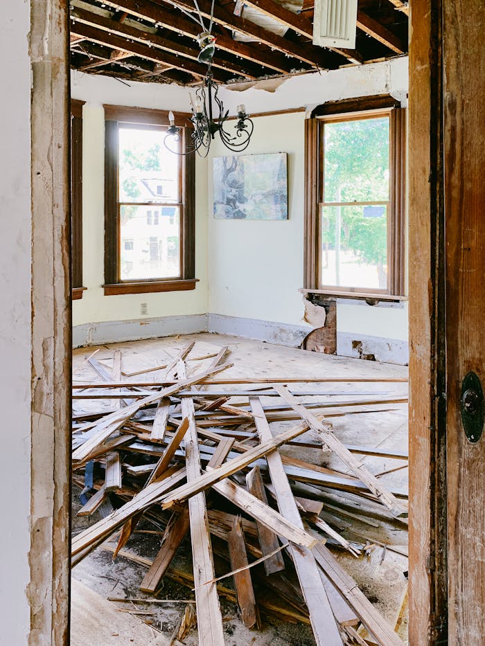Interior room under renovation with exposed beams and planks piled on the floor.